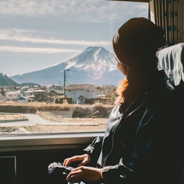 Enjoying travel. Young pretty woman traveling by the train from sitting near the window and looking mountain Fuji. vintage filter. Travel concept